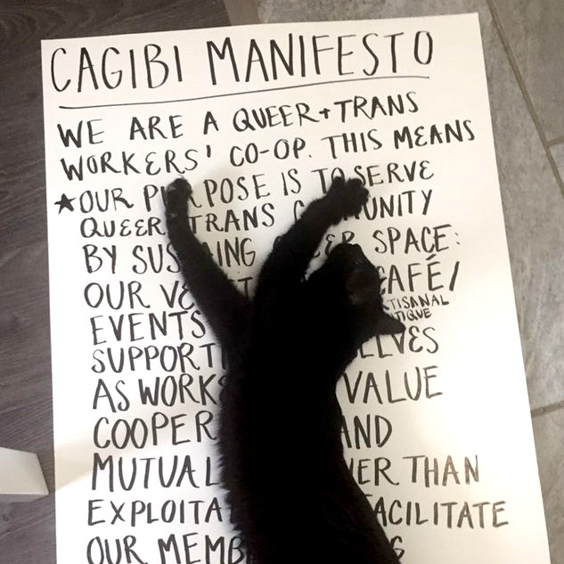 un chat couché sur une affiche sur laquelle on voit le titre Cagibi Manifesto